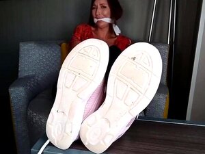 Schau zu, wie die gefesselte Frau Schuhe und Socken ausgezogen