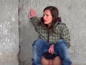 Heiße Brünette pisst auf einer Bank im Park. Brünette Süße sitzt